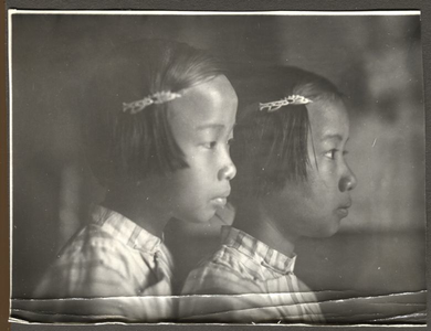 229296 Twee jonge Chinese meisjes poseren te Merauke (Indonesië). Zijaanzicht